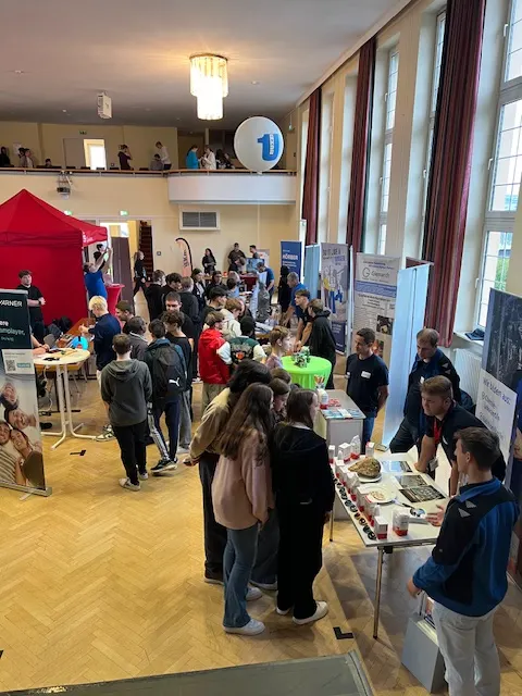 Blick in eine volle Halle mit Ständen der Ausbildungsbetriebe