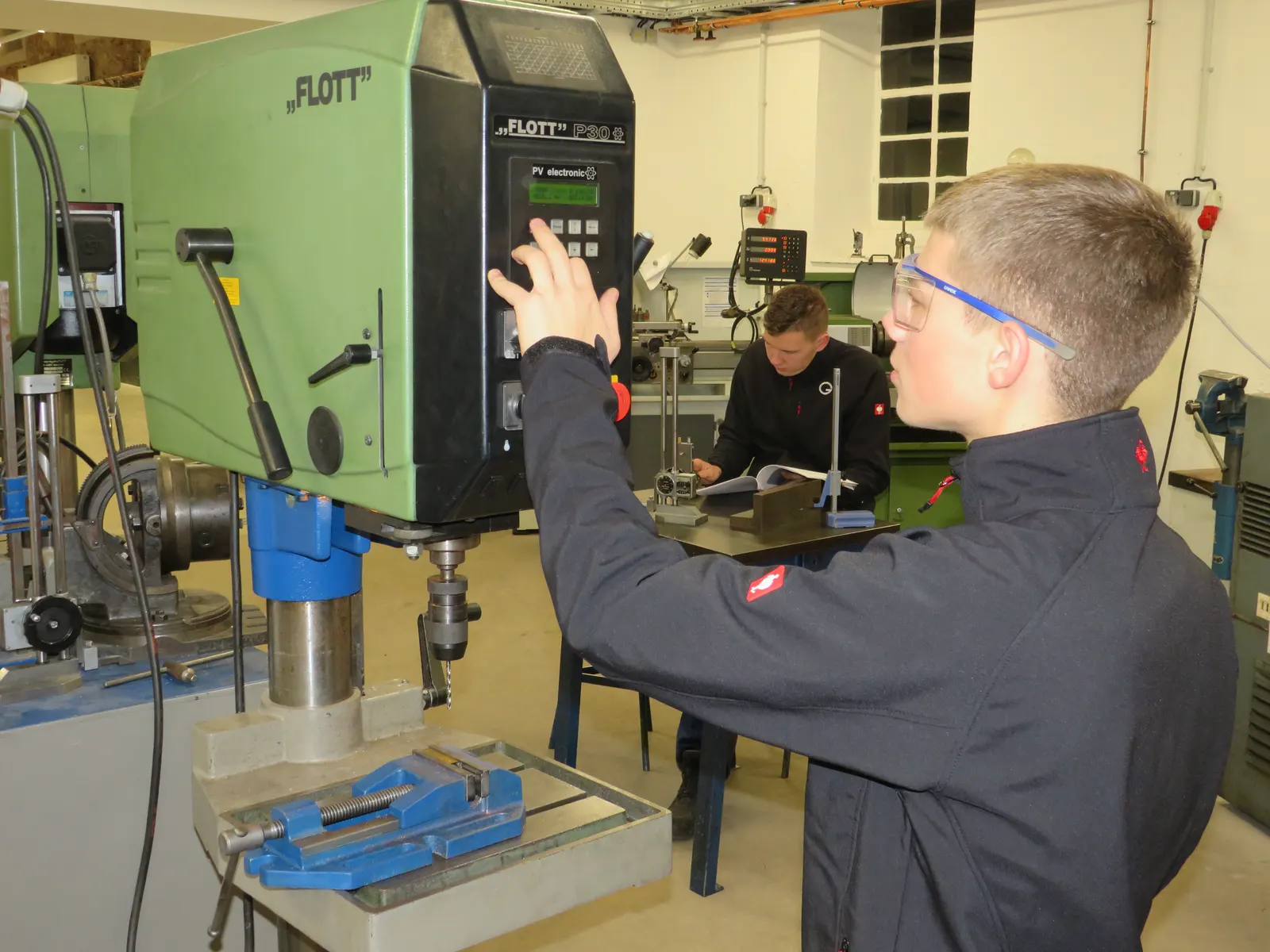 Auszubildender an einer Bohrmaschine in der Lehrwerkstatt