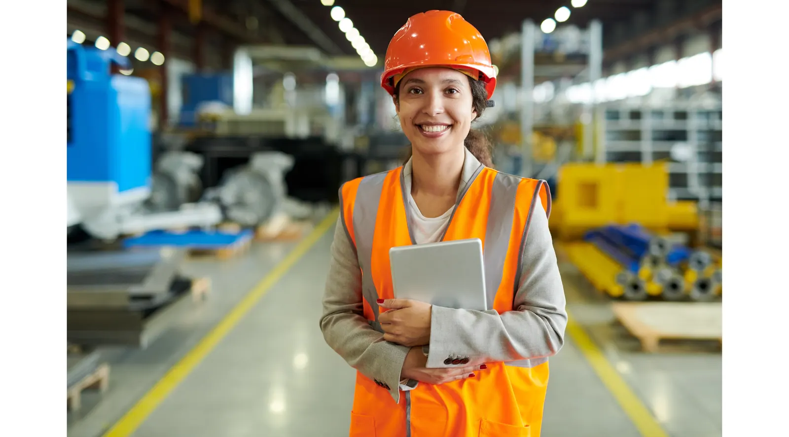 Auszubildende mit Schutzhelm und Warnweste in der Produktion