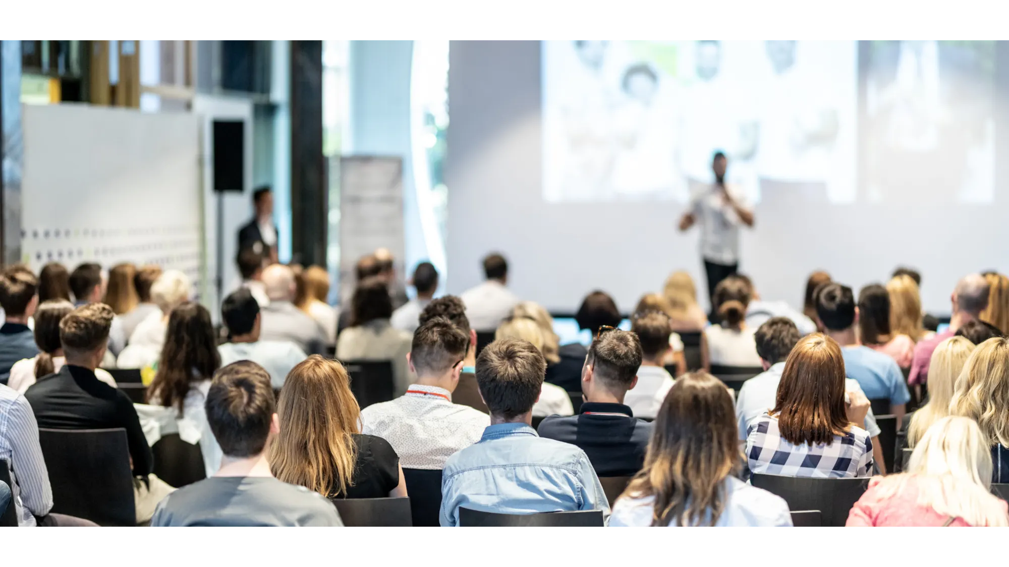 Publikum bei einer Informationsveranstaltung, vorne spricht ein Redner